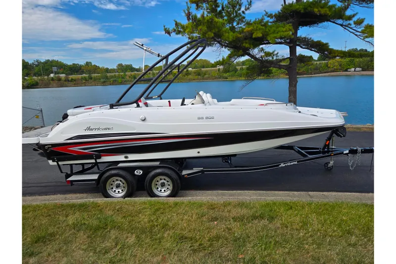 Slide: The Image of 2020 Hurricane SunDeck Sport 202 IO boat on trailer by a lake. - 9