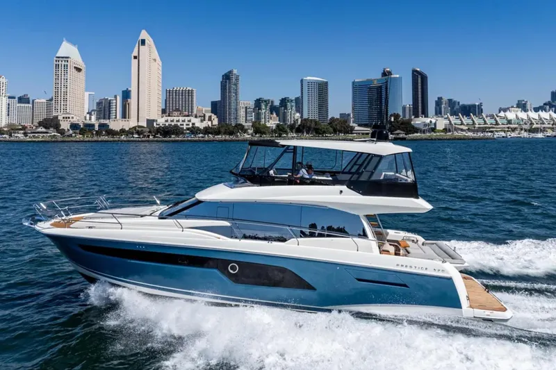 Slide: The Image of Luxury 2019 Prestige 520 yacht cruising near city skyline on a sunny day. - 32