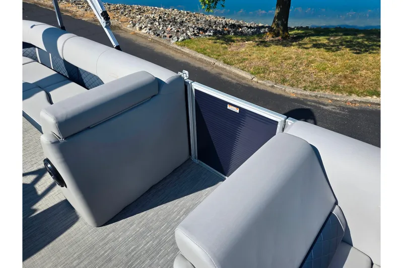 Slide: The Image of 2022 Bennington L 22 L-Bench pontoon boat interior with gray seating and scenic lakeside view. - 12