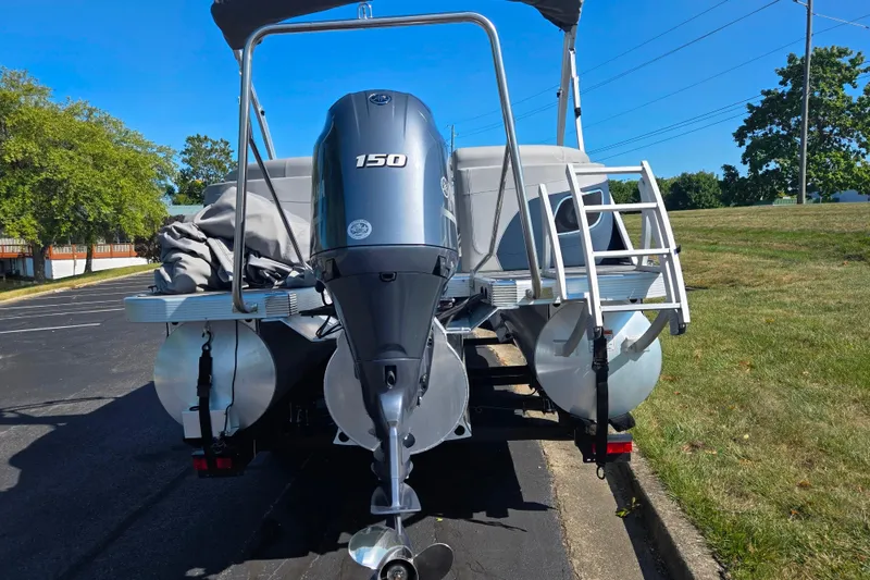 Slide: The Image of 2022 Bennington L 22 L-Bench pontoon boat with 150 HP engine, parked outdoors. - 2