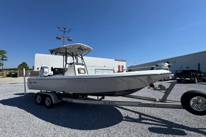 Slide: The Image of 2022 Sea Born FX25 Bay boat on trailer, parked outdoors under clear blue sky. - 7