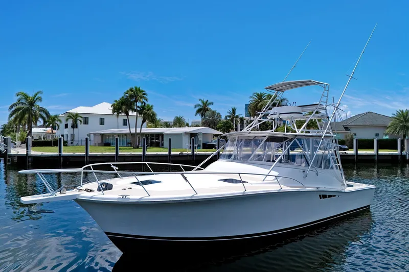 The Image of 1994 Luhrs 38 yacht on calm water, with palm trees and luxury homes in the background. - 1