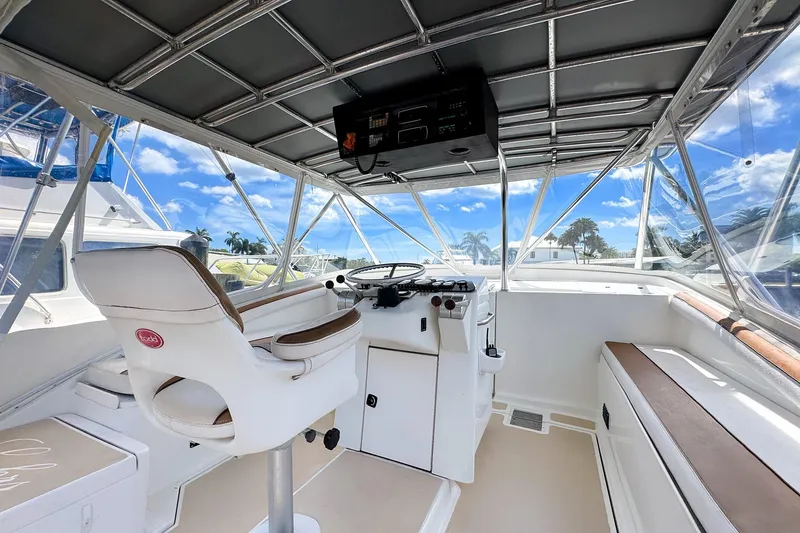 Slide: The Image of 1994 Luhrs 38 boat helm with white seating, steering wheel, and clear canopy. - 10