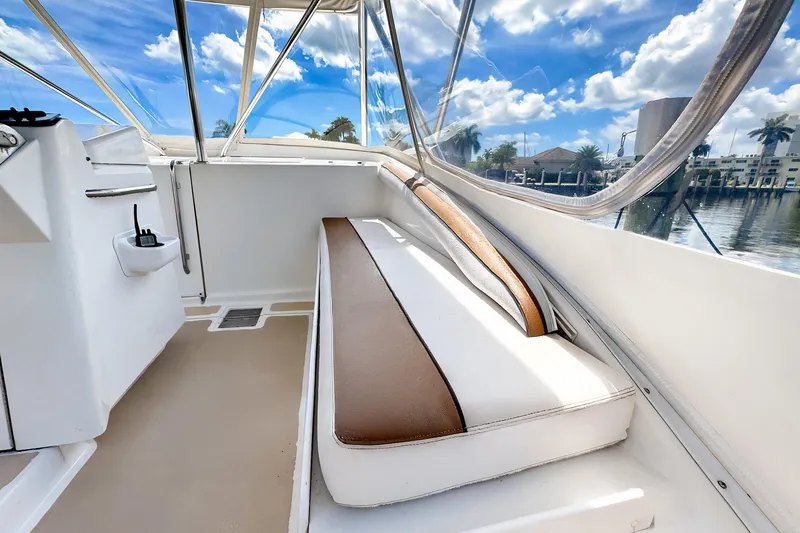Slide: The Image of 1994 Luhrs 38 boat interior with cushioned seating and clear windows, under a blue sky. - 12