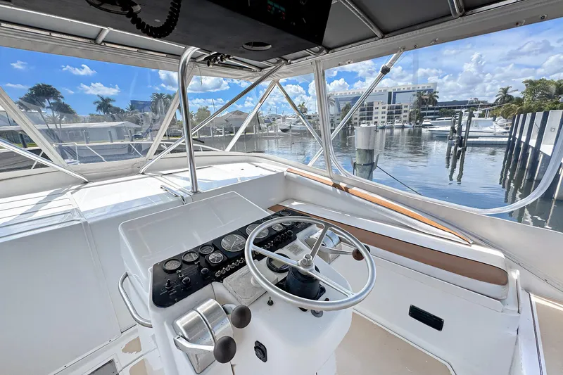 Slide: The Image of 1994 Luhrs 38 boat helm with marina view, featuring steering wheel and control panel. - 15