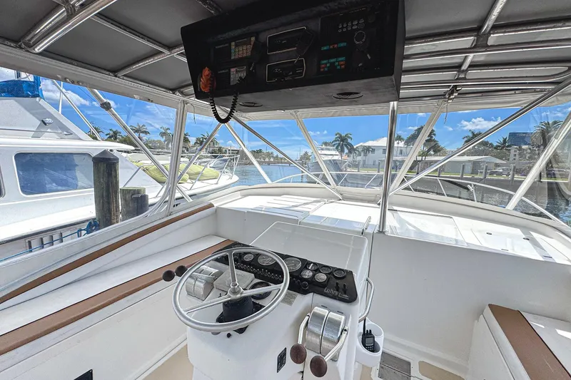 Slide: The Image of 1994 Luhrs 38 boat helm with steering wheel and control panel, docked in sunny marina. - 16