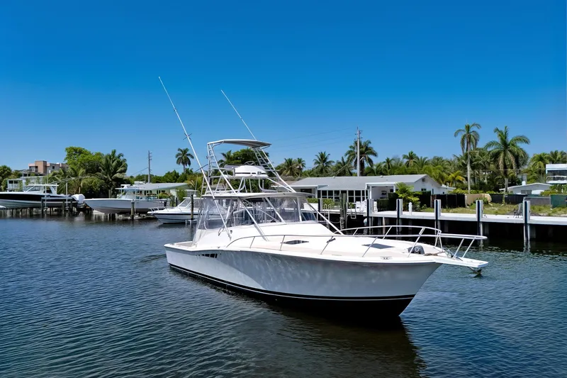 Slide: The Image of 1994 Luhrs 38 boat on calm water, surrounded by palm trees and docks. - 2