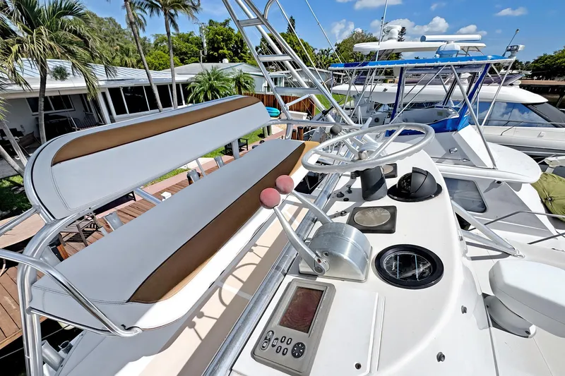 Slide: The Image of 1994 Luhrs 38 boat helm with steering wheel, controls, and seating, docked near palm trees. - 22