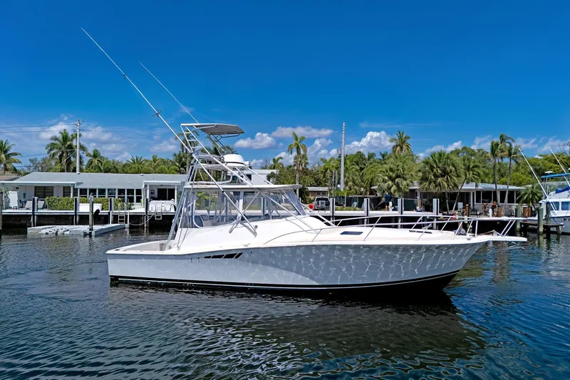 Slide: The Image of 1994 Luhrs 38 boat docked in a tropical marina under a clear blue sky. - 40