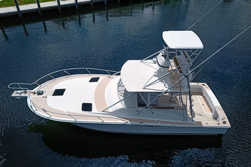 Slide: The Image of 1994 Luhrs 38 boat on calm water, featuring a spacious deck and flybridge. - 8