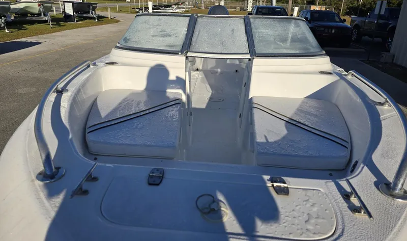 Slide: The Image of 2002 Angler 180DC boat interior with seating and windshield, parked outdoors. - 3