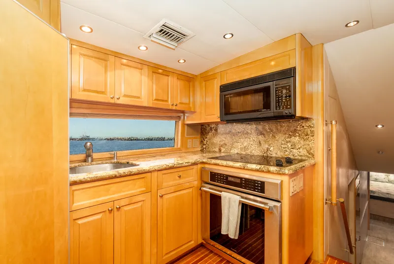Slide: The Image of Luxurious kitchen interior of 2000 Hatteras 70 Convertible yacht with wood cabinetry and ocean view. - 29