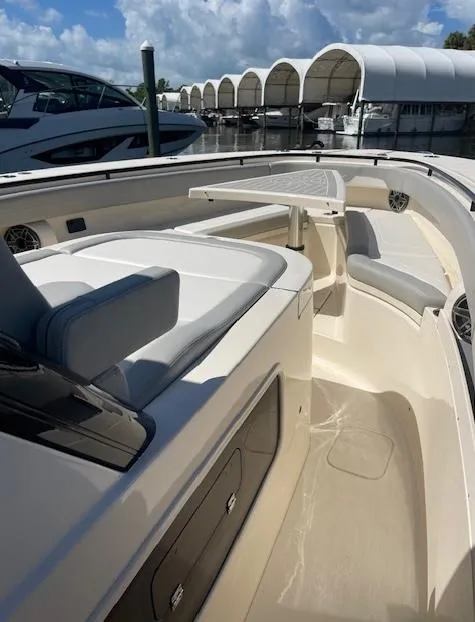 Slide: The Image of 2022 Scout 355 LXF CC boat interior with seating and storage, docked near covered slips. - 5