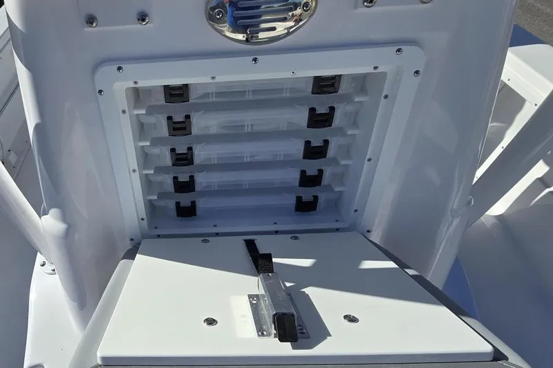 Slide: The Image of 2026 NauticStar 224 Bay boat storage compartment with multiple shelves and secure latch. - 19
