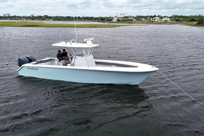 Slide: The Image of 2013 SeaHunter 33 Tournament boat on calm water, featuring dual outboard motors. - 4