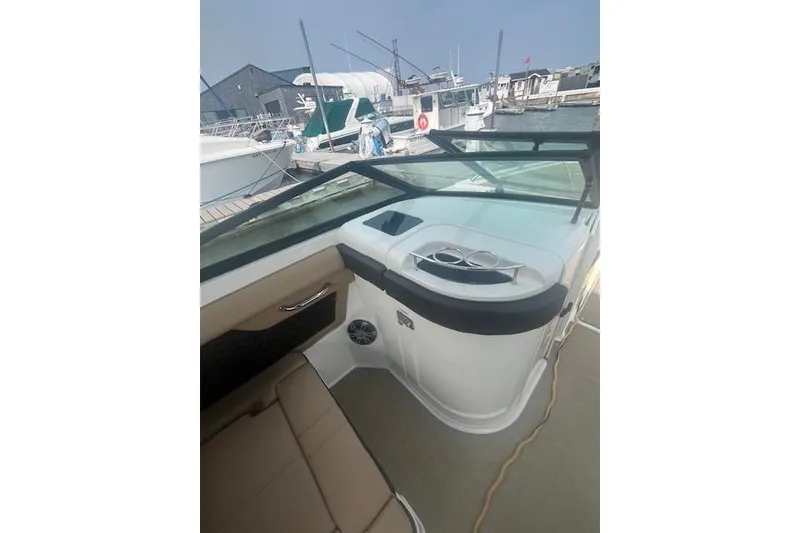 Slide: The Image of 2019 Sea Ray SDX 270 boat interior with seating and cup holders at a marina. - 11