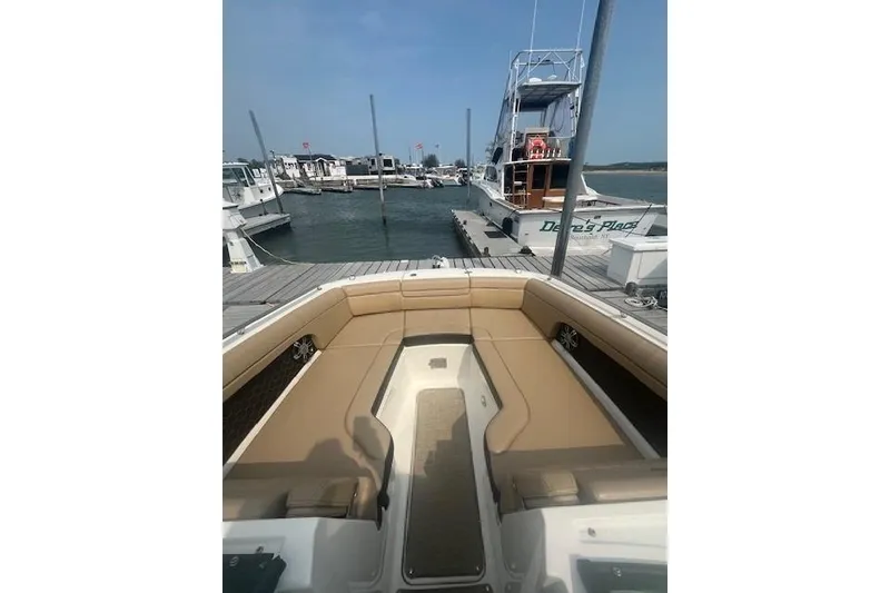 Slide: The Image of 2019 Sea Ray SDX 270 boat docked, featuring spacious seating and a clear sky. - 6