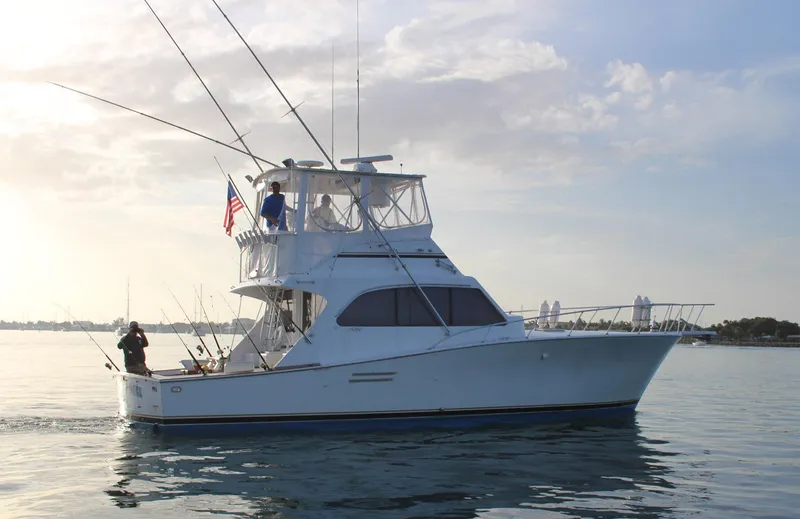 Slide: The Image of 1990 Post 44 Sport Fisherman boat on calm water, with fishing rods and American flag. - 1