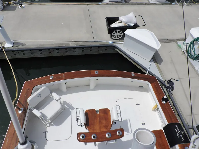 Slide: The Image of 1990 Post 44 Sport Fisherman boat docked, featuring a wooden deck and fishing chair. - 19