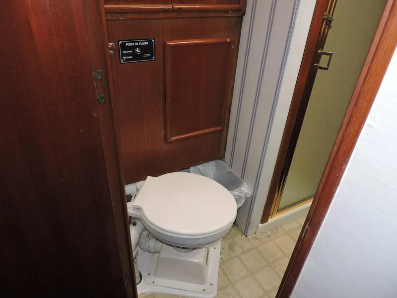 Slide: The Image of 1990 Post 44 Sport Fisherman boat bathroom with wooden paneling and compact toilet. - 44