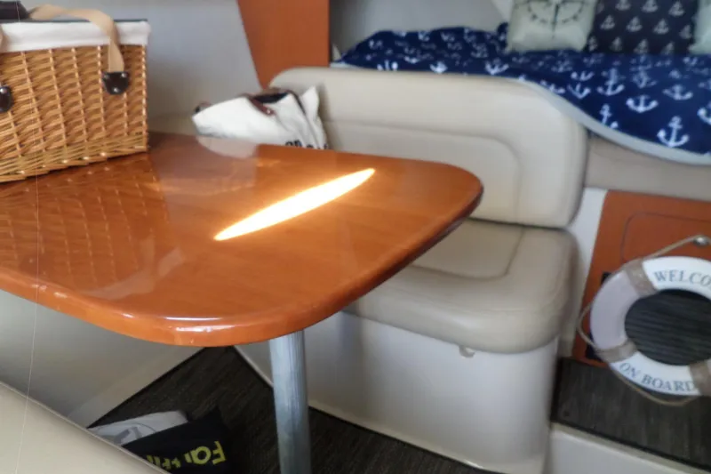 Slide: The Image of Interior of 2005 Chaparral Signature 270 with wooden table and cushioned seating. - 35