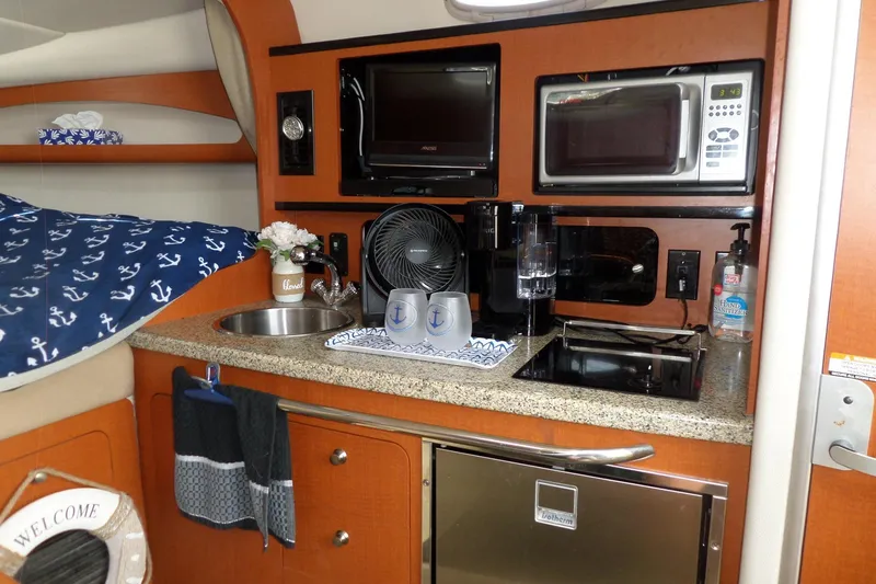 Slide: The Image of 2005 Chaparral Signature 270 cabin kitchen with microwave, sink, and nautical decor. - 47