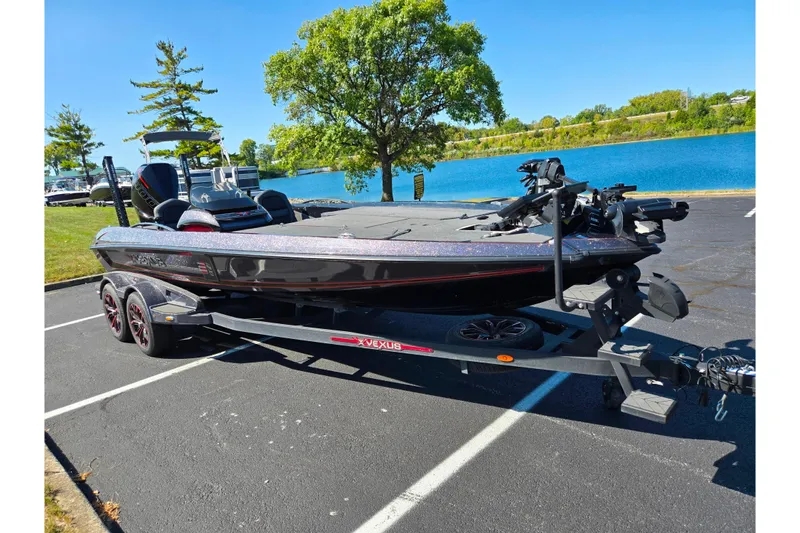 Slide: The Image of 2025 Vexus VX21 boat on trailer by a lake, under clear blue sky. - 2