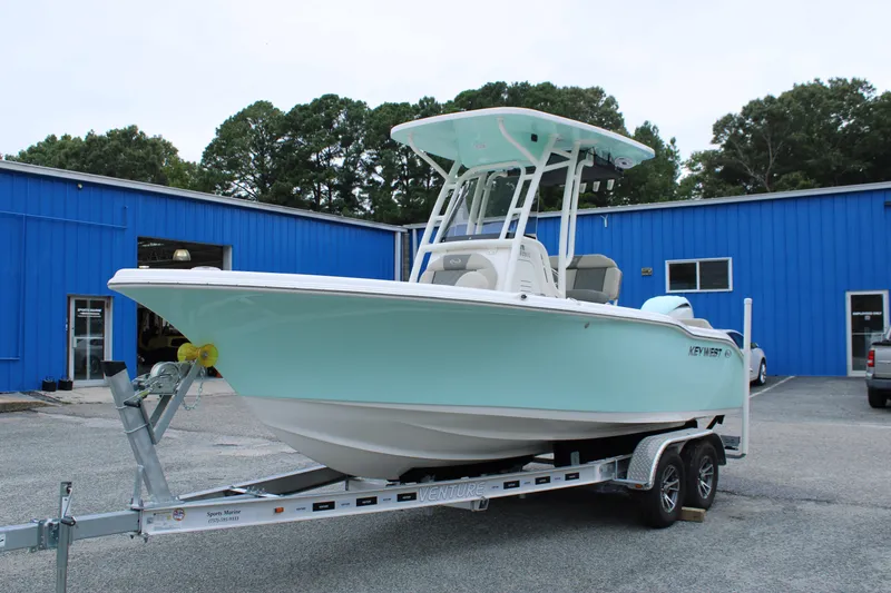 Slide: The Image of 2026 Key West 219 FS boat on trailer, parked outside blue building. - 6