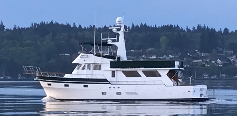 The Image of 1980 Willard Marine Pilothouse yacht cruising on a calm lake with forested shoreline. - 0