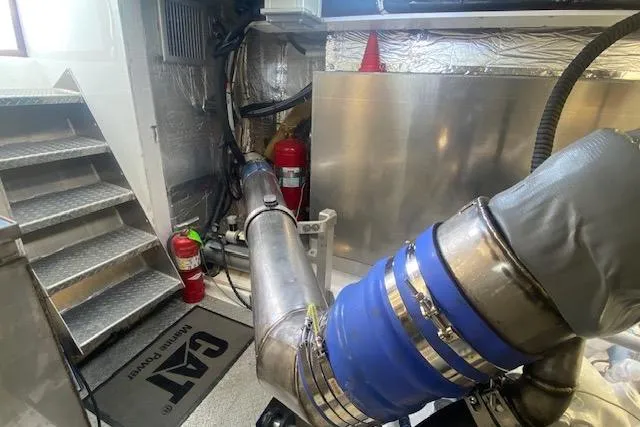 Slide: The Image of Engine room of a 1980 Willard Marine Pilothouse with visible exhaust system and fire extinguishers. - 35