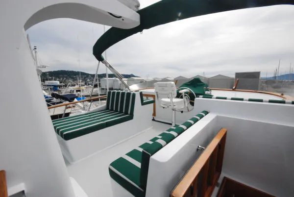 Slide: The Image of 1980 Willard Marine Pilothouse boat with green-striped seating, docked at a marina. - 41