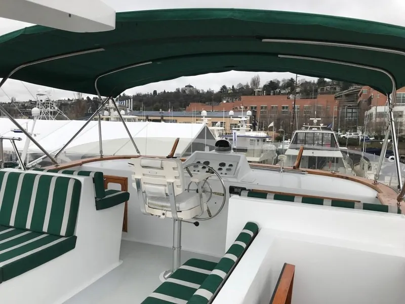 Slide: The Image of 1980 Willard Marine Pilothouse boat with green canopy and striped seating at a marina. - 42