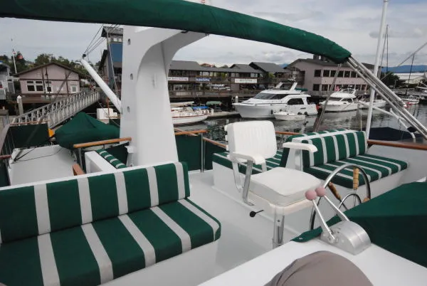 Slide: The Image of 1980 Willard Marine Pilothouse boat with green-striped seating, docked at a marina. - 44