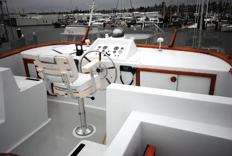 Slide: The Image of 1980 Willard Marine Pilothouse boat helm with steering wheel and controls, docked at a marina. - 48