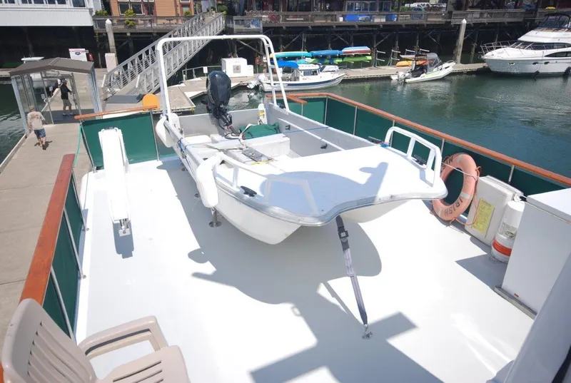 Slide: The Image of 1980 Willard Marine Pilothouse boat docked, featuring a small dinghy on deck. - 49
