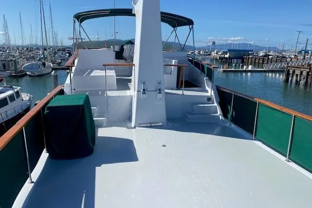 Slide: The Image of 1980 Willard Marine Pilothouse boat docked in a marina, featuring spacious deck and green awnings. - 55