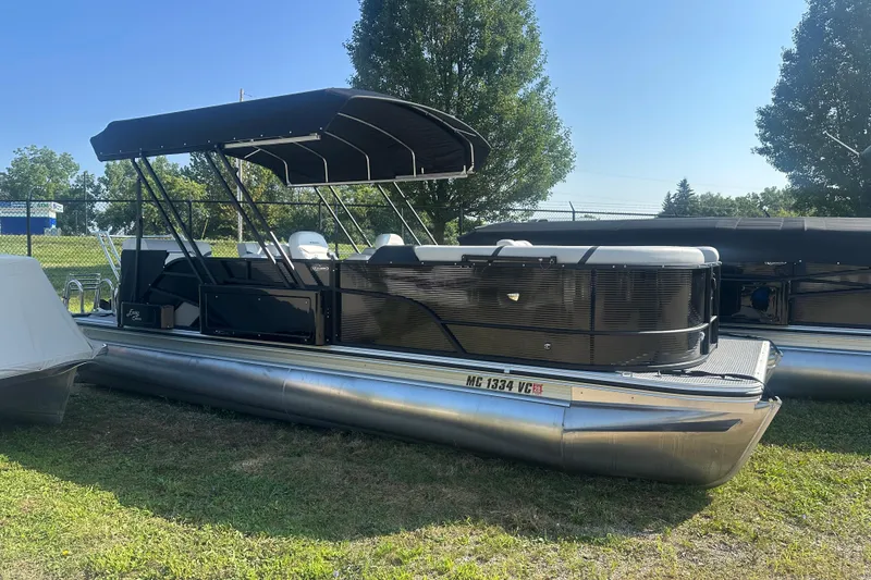 The Image of 2025 Crest Classic 220 pontoon boat with canopy, parked on grass under clear sky. - 0