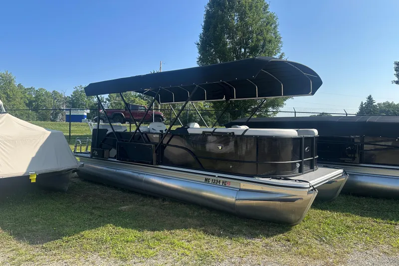 Slide: The Image of 2025 Crest Classic 220 pontoon boat with canopy, parked on grass under clear sky. - 1