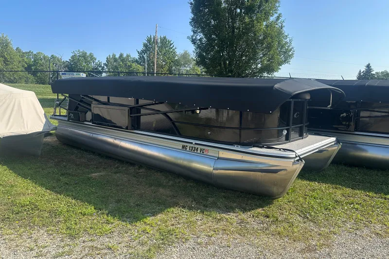 Slide: The Image of 2025 Crest Classic 220 pontoon boat with black canopy, parked on grass. - 3