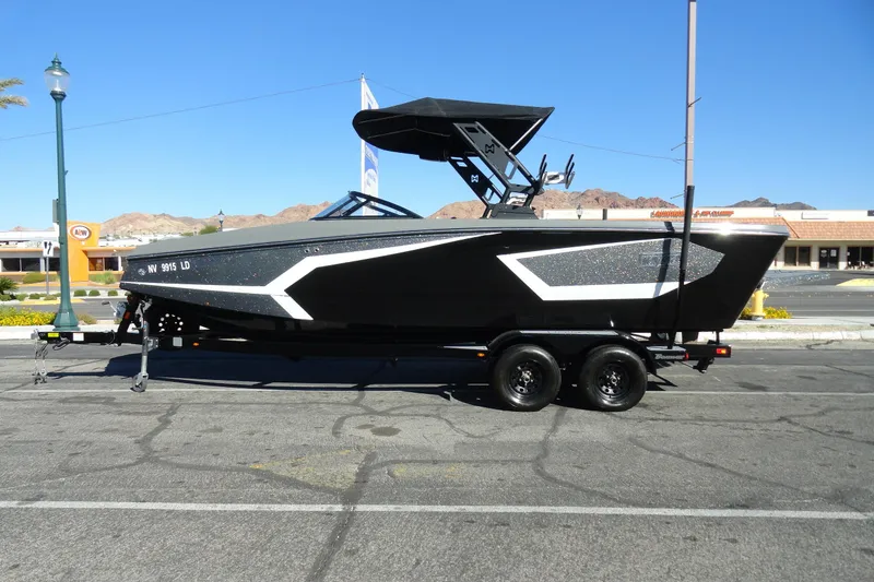 The Image of 2022 Heyday WT Surf boat on trailer, parked in urban setting under clear blue sky. - 1