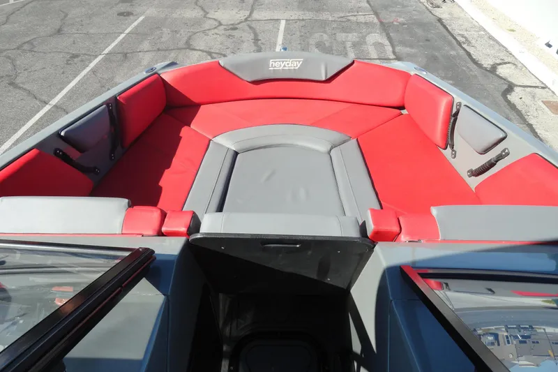 Slide: The Image of 2022 Heyday WT Surf boat interior with red and gray seating, docked on pavement. - 18