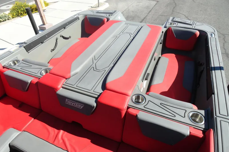 Slide: The Image of 2022 Heyday WT Surf boat interior with red and gray seating, cup holders, and sleek design. - 20