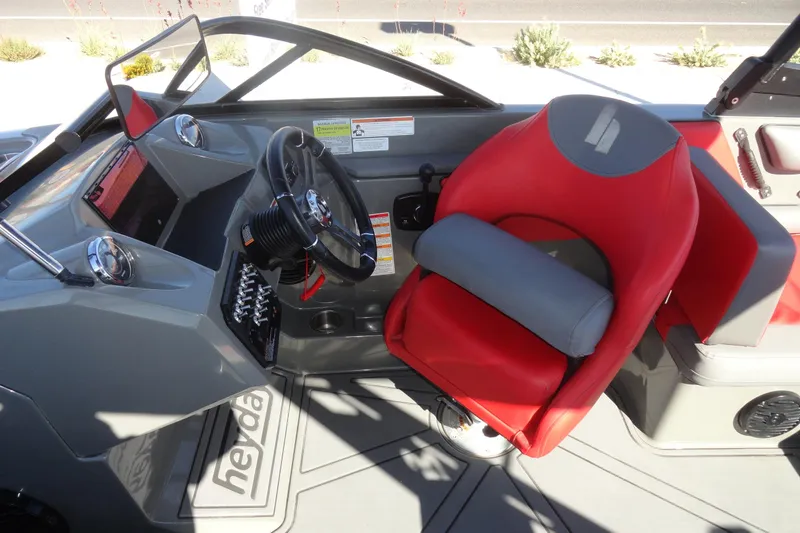 Slide: The Image of 2022 Heyday WT Surf boat interior with red and gray captain's seat and steering wheel. - 12