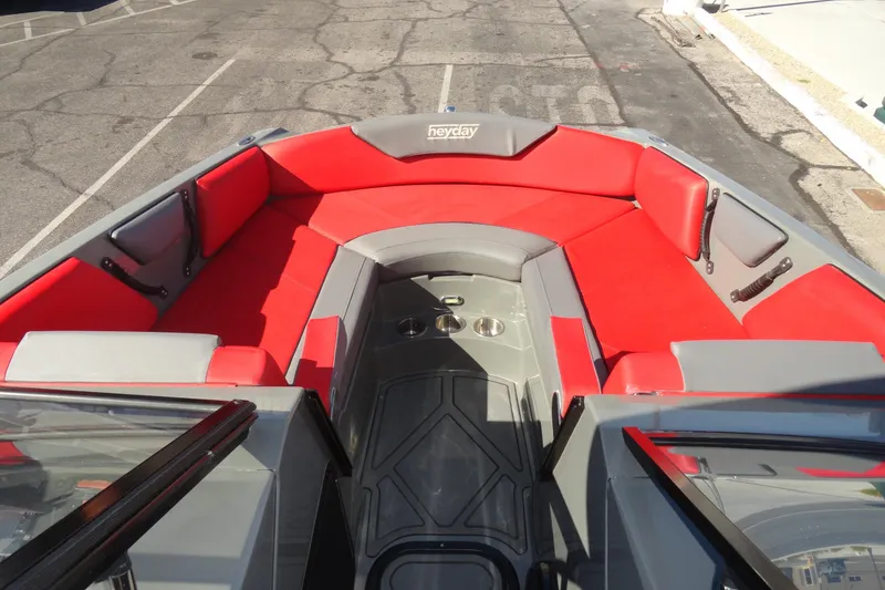 Slide: The Image of 2022 Heyday WT Surf boat interior with red and gray seating, cup holders, and open deck. - 17