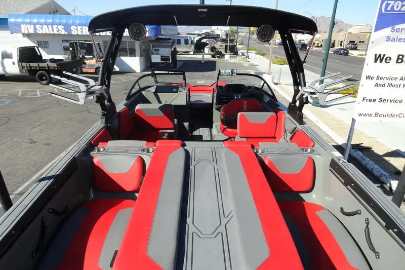 Slide: The Image of 2022 Heyday WT Surf boat interior with red and gray seating, parked at RV sales lot. - 6