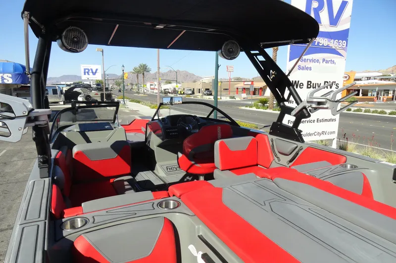 Slide: The Image of 2022 Heyday WT Surf boat interior with red and gray seating, parked near RV dealership. - 7