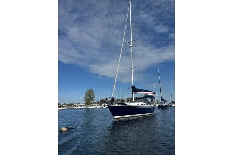 Slide: The Image of 1988 C&C 44 sailboat anchored in a marina under a clear blue sky. - 2