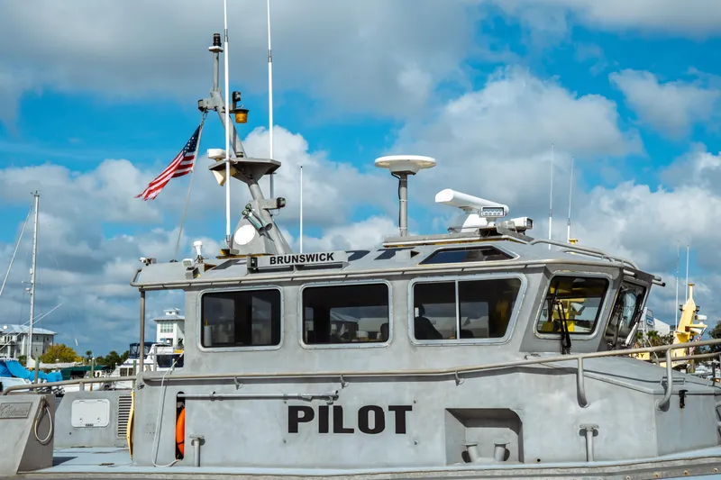 Slide: The Image of 2004 Kvichak Marine Industries Pilot boat docked, featuring American flag and clear blue sky. - 8