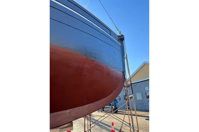 Slide: The Image of Custom 2004 Luke Powell Pilot Cutter in dry dock, showcasing its hull and vibrant paintwork. - 12