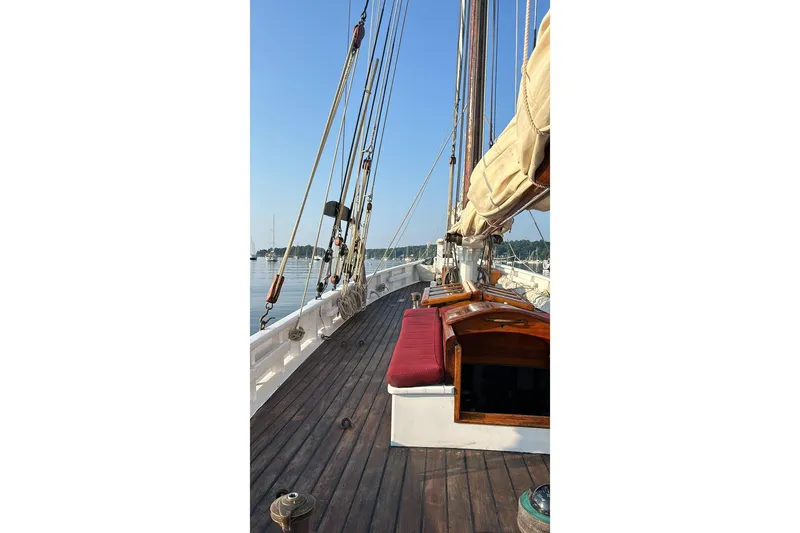 Slide: The Image of Wooden deck of 2004 Custom Luke Powell Pilot Cutter with rigging and red cushions. - 13